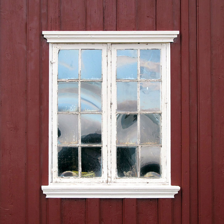 Et originalt vindu med slanke sprosser og vinkelbeslag. Her kan bare det ene vindusfaget åpnes. Legg merke til det vakre spillet i det håndlagede glasset.