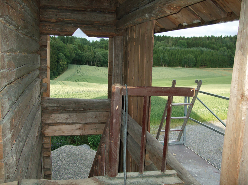 Utsikt mot skog og jorder fra svalgangen i andre etasje før den paneleres.